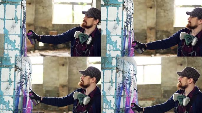 迷人的大胡子家伙拿着气溶胶油漆，在宽敞的废弃房子里的柱子上画涂鸦。有创造力的人，空荡荡的建筑和现代艺