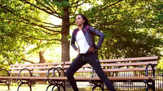 年轻的黑人妇女在公园的长凳上伸展，全长