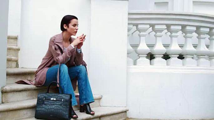时尚意识强的年轻女子坐在城市建筑的台阶上