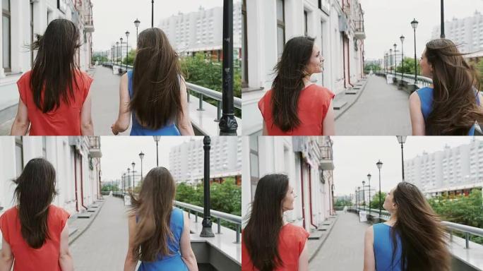 风吹起长长的黑发美丽的年轻女性走在街上经过商店，后视图，慢镜头拍摄