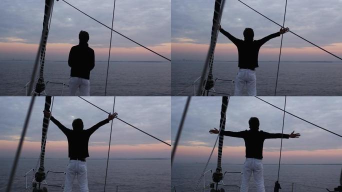 人在海里的帆船上以放松的方式举手。