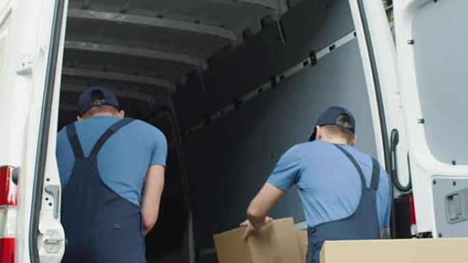 两名强壮的送货员慢动作装载装满纸箱的商用车。