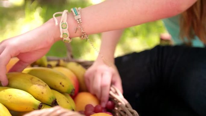 女人的手从水果篮里拿香蕉