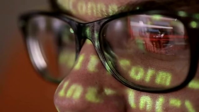 电脑代码反射在黑暗中浏览的人的眼镜。网络成瘾概念