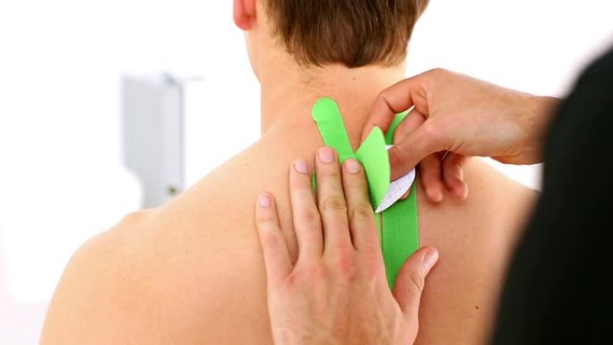 物理治疗师将绿色kinesio胶带应用于患者背部