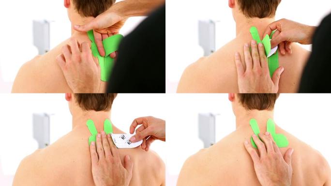 物理治疗师将绿色kinesio胶带应用于患者背部