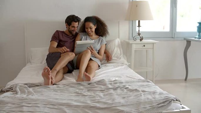 夫妇坐在床上看着数字平板电脑