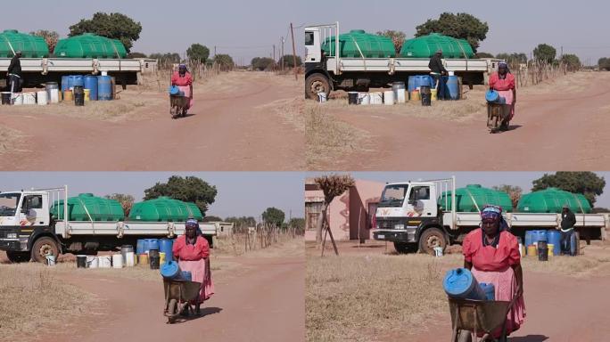 一位非洲老妇从油轮上取水，然后用独轮车将其推回家中。