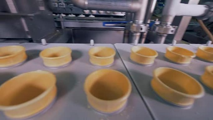 在productin生产线上用冰淇淋填充空的晶片锥。