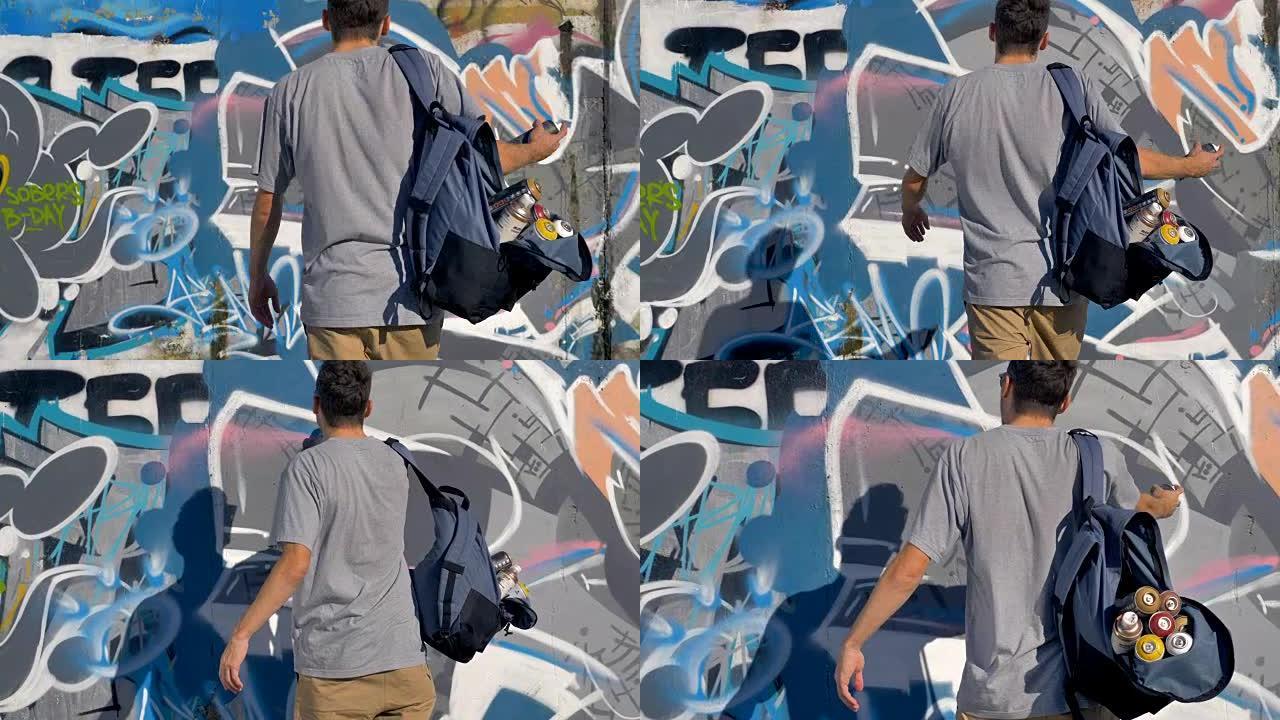 一位男性涂鸦艺术家在涂鸦墙上添加了另一种喷漆。