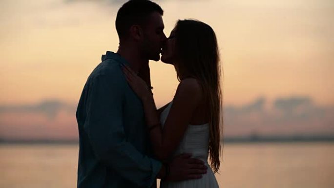 爱情情侣在黄昏接吻的剪影