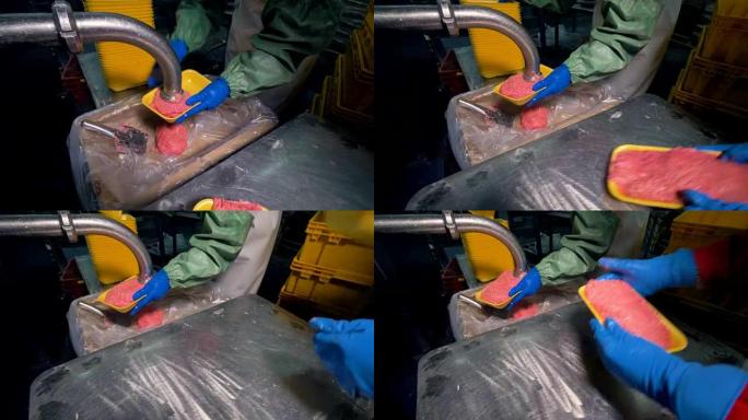 一名工人用碎肉填充塑料托盘。