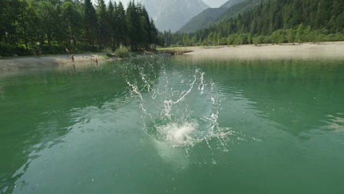 慢镜头特写: 年轻女子跳进高山下美丽的山湖