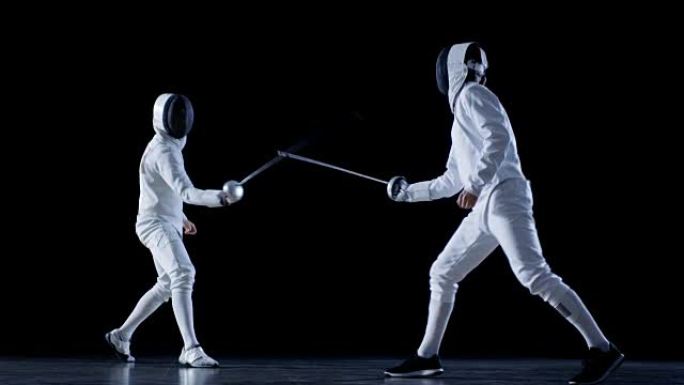两名专业装备齐全的击剑手熟练地用箔纸战斗。他们进攻、防守、跳跃、推力和弓步。以慢动作和孤立的黑色背景