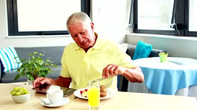 退休男子吃早餐时使用平板电脑