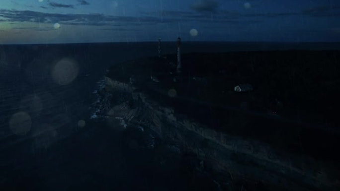 空中无人机夜景拍摄雨中悬崖上的灯塔。