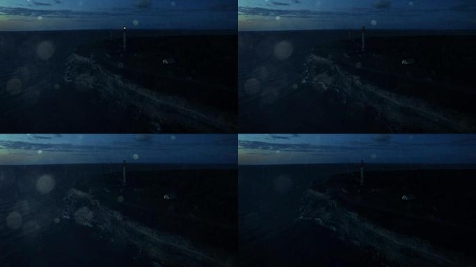 空中无人机夜景拍摄雨中悬崖上的灯塔。