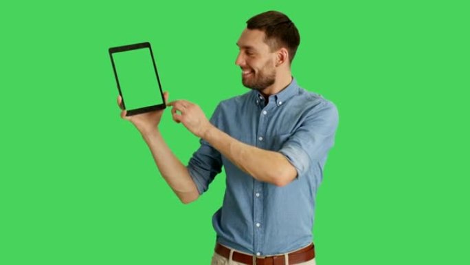 一个时髦的男人用一只手拿着平板电脑，用另一只手滑动触摸手势。平板电脑和背景是绿色屏幕。