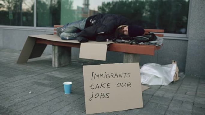 由于欧洲的移民危机，无家可归和失业的欧洲男子在城市街道的长凳上睡觉