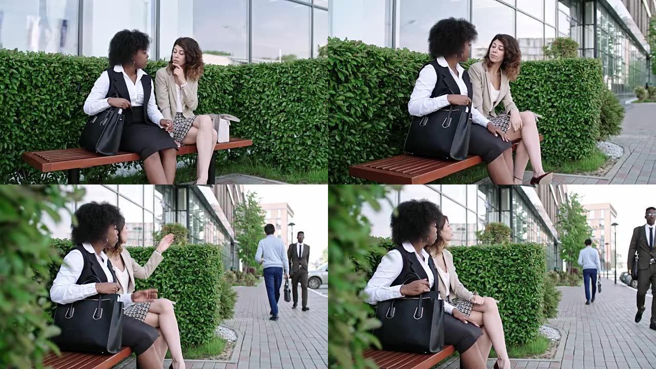 两个女商人坐在户外长凳上闲聊