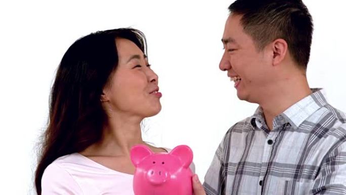 亚洲夫妇在亲吻自己时拿着存钱罐