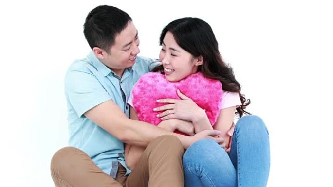 微笑的亚洲夫妇坐在一起抱着枕头