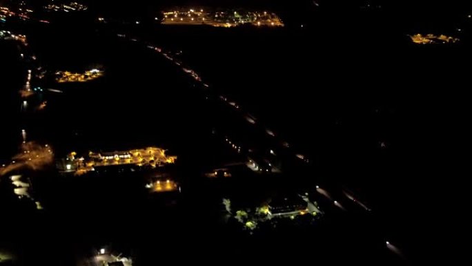 空中: 夜间沿着繁忙的高速公路穿越居民区的汽车