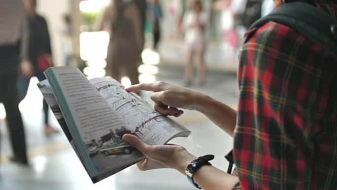 游客步行和使用指南手册中的地图寻找带数字平板电脑的地铁地图