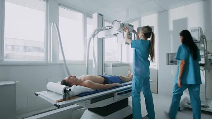 在医院里，低角度拍摄的男子躺在床上，女技师调整x光机。扫描骨折，四肢骨折，损伤，癌症或肿瘤。拥有技术