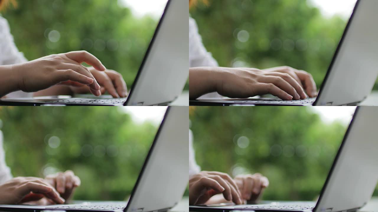 女人用手在绿色背景的笔记本电脑键盘上打字，在家工作