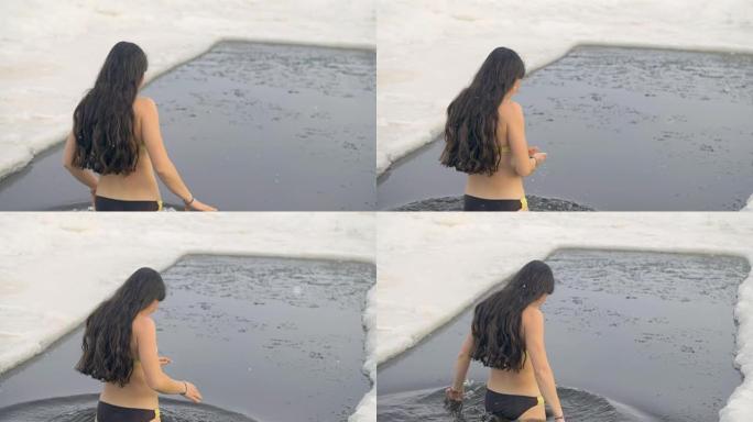一个穿着泳衣的女人在冰冻的水中慢慢走。