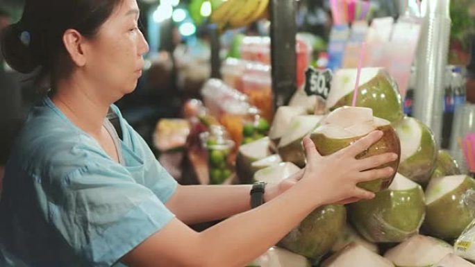 妇女在泰国街头食品上购买椰子