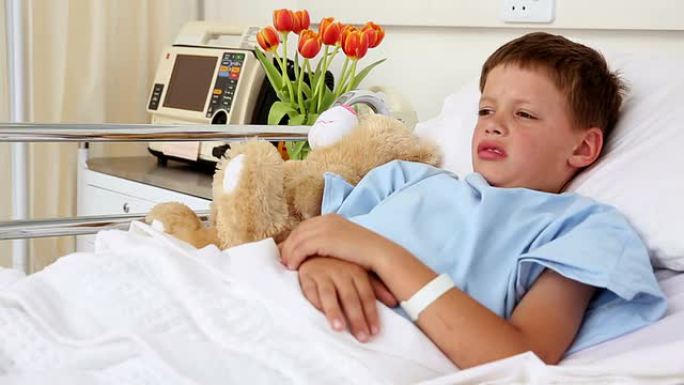 生病的小男孩和泰迪熊躺在床上