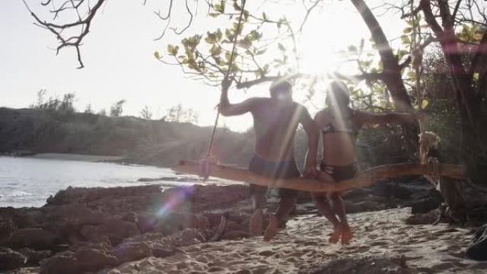 4k慢动作: 迷人的夏威夷夫妇在海滩旁共享绳索秋千