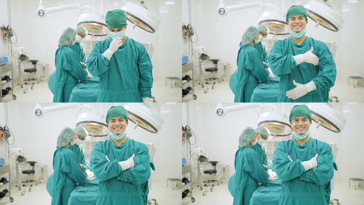高加索男性外科医生的肖像穿着完整的手术磨砂膏微笑着相机，团队医生在医院手术室为病人做手术。
