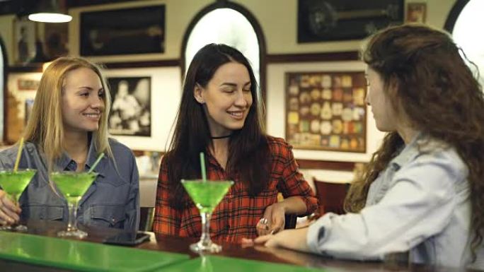 开朗的女学生坐在酒吧的柜台旁时会情绪激动。穿着便服的女孩在分享新闻和大笑。年轻人在空闲时间的概念中玩