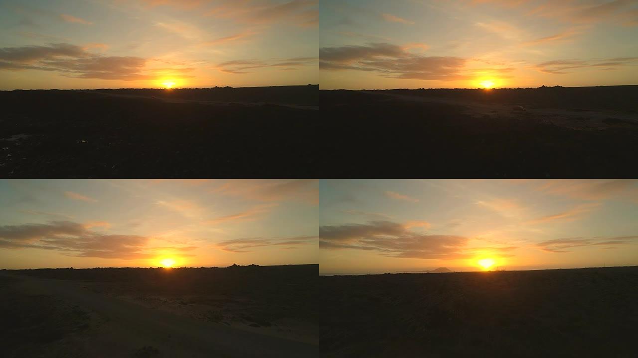 在令人惊叹的金色日落时，空中汽车在富埃特文图拉的道路上行驶。
