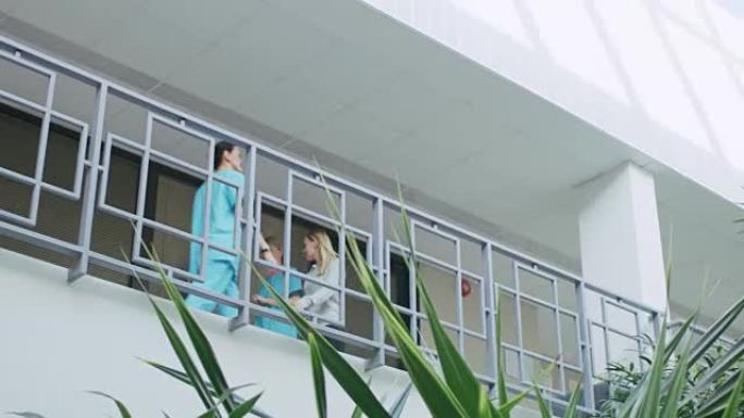 在医院低角度拍摄，护士和病人在二楼散步，交谈。干净，新医院有专业人员。慢动作。