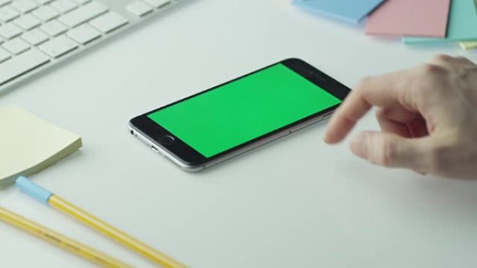 设计师在横向模式下使用带有绿屏的手机。顶视图。
