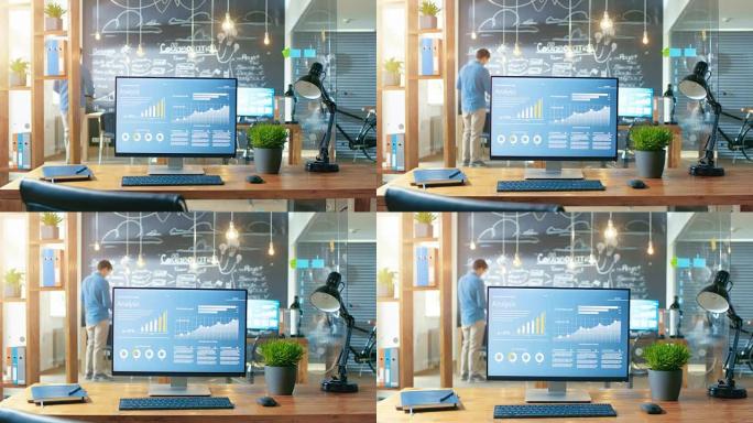 显示器上显示的带有移动应用程序设计的个人计算机站在办公桌上，背景是在白天办公环境中工作的人。