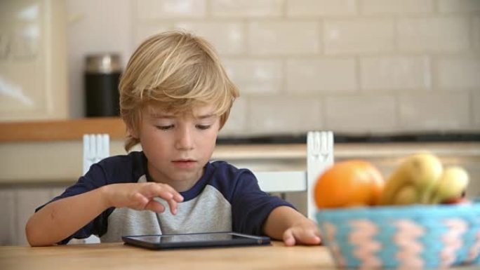 小男孩在餐桌上使用平板电脑