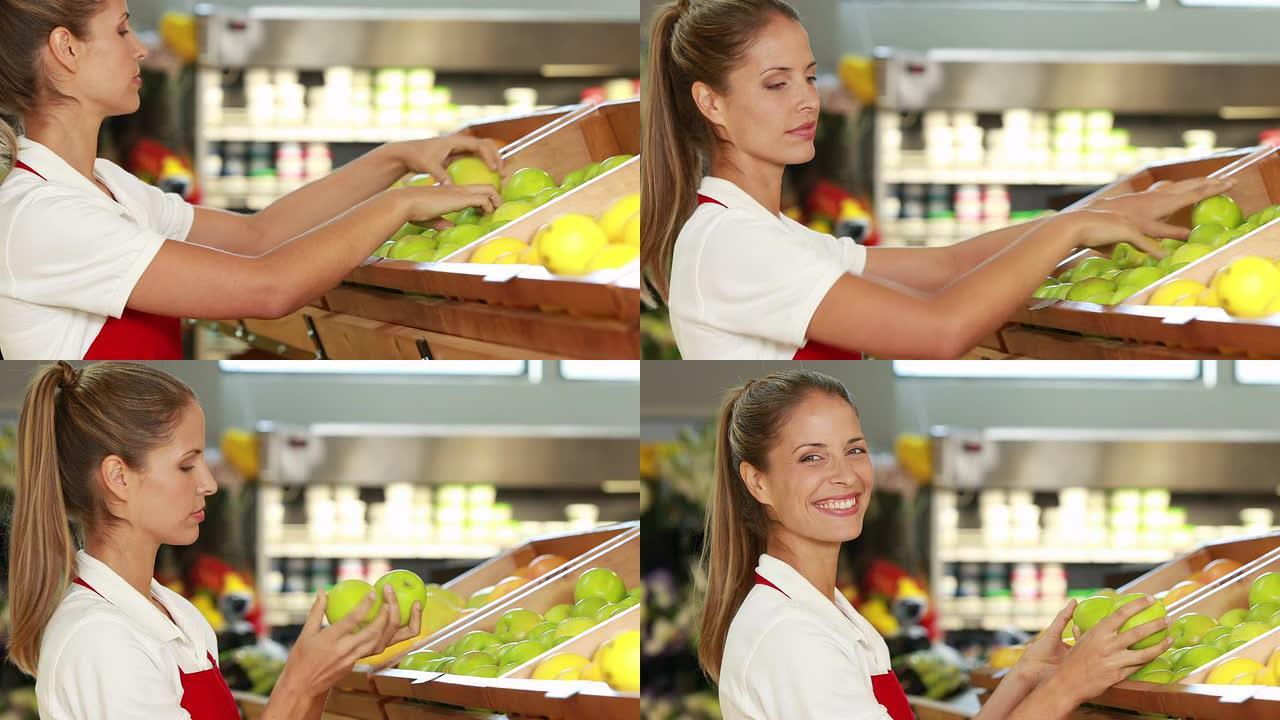 漂亮的工人在超市里放水果
