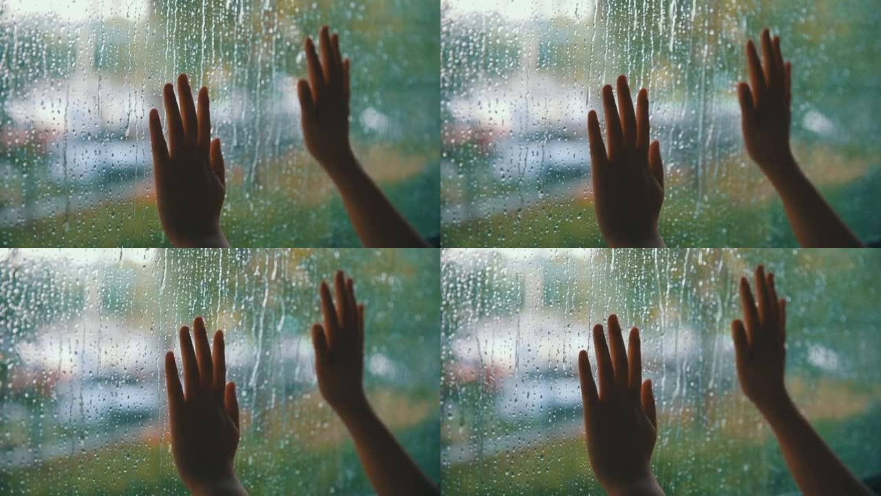 女人用手触摸雨滴的窗户