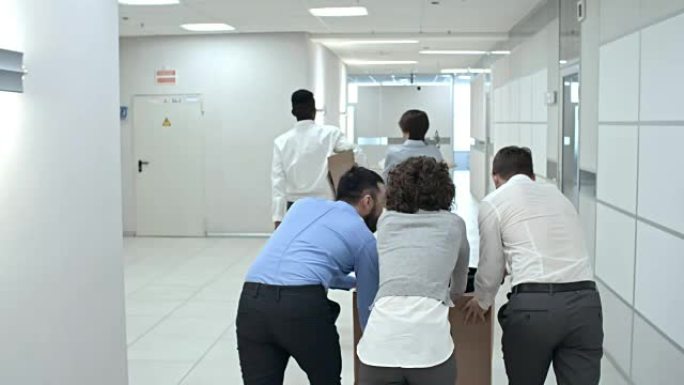 业务团队通过办公室走廊推纸箱