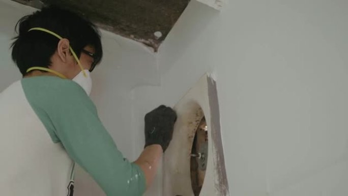 年轻人在厨房房间里爬梯和清洁排气扇。