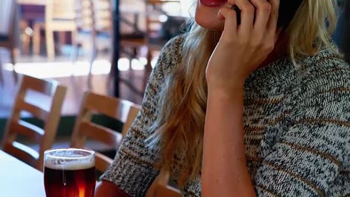 女人在4k酒吧喝啤酒时在手机上聊天