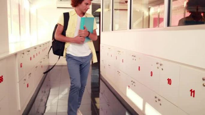 英俊的学生把笔记本放在他的储物柜里
