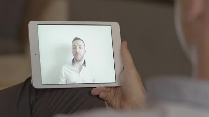 白人男子通过视频会议进行商务谈话。同事通过平板电脑互相打电话。