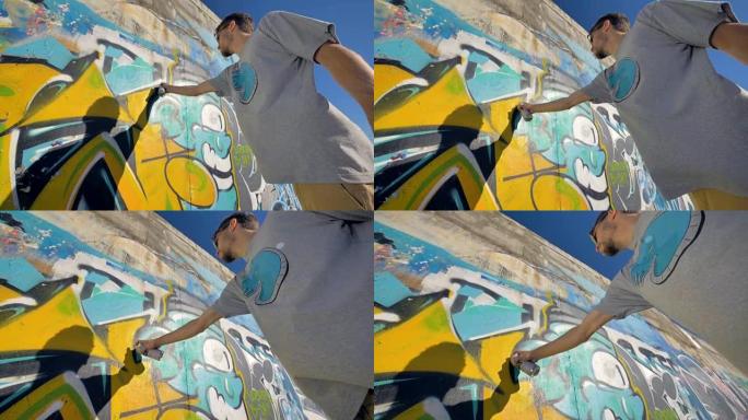 涂鸦艺术家正在墙上画一个黄色的字母，从左边看，从下面看。