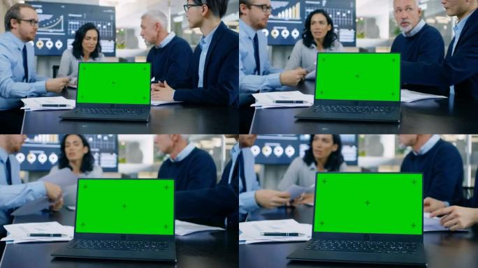 在会议室的笔记本电脑中，会议桌上带有绿色色度键屏幕。在后台，商务人士有重要的讨论。